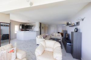 a living room with white furniture and a kitchen at SAVINKA in Ancient Epidauros