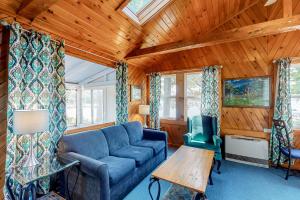 ein Wohnzimmer mit einem blauen Sofa und einer Holzdecke in der Unterkunft Pines Cottage in Standish