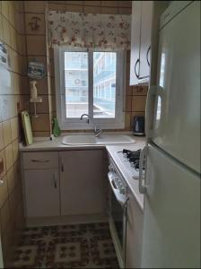 une cuisine avec évier et cuisinière ainsi qu'une fenêtre dans l'établissement Apartamento Playa Blanca, à Dénia