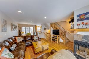 a living room with a leather couch and a fireplace at Saw Mill Station 127 in Winter Park