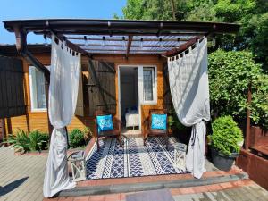 a pergola on a deck with chairs and a house at Słonecznik Jastarnia. Domek na Zdrojowej. in Jastarnia