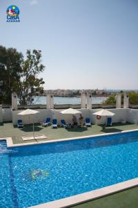 a swimming pool with umbrellas and chairs next to the water at Apartamentos Marino Superior Casa Azahar in Alcossebre