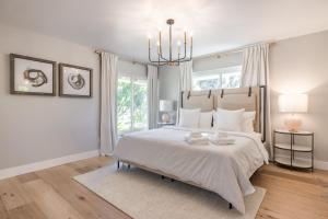 a white bedroom with a large bed with a chandelier at @ Marbella Lane - Modern and Luxurious Design Home in Fullerton
