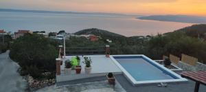 a house with a swimming pool and a view of the water at Holiday home Duje in Veliko Brdo