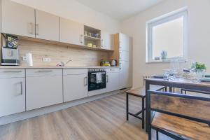 a kitchen with white cabinets and a wooden table at Ostseeapartment_80m2_3xSchlafzimmer_2xParkplatz_Netflix_Waschtrockner in Cottbus
