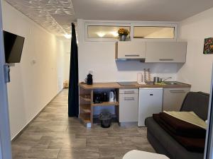 uma cozinha com armários brancos e um sofá num quarto em Apartmenthaus Suskovic Insel Krk em Omišalj