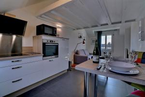 una cucina con armadi bianchi e un bancone con tavolo di Appartement "MEZZA" centre ville de VITRÉ a Vitré