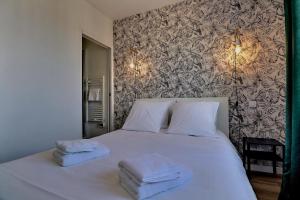 Un dormitorio con una cama blanca con toallas. en Appartement "MEZZA" centre ville de VITRÉ, en Vitré