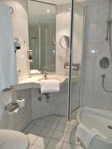 a bathroom with a shower and a sink and a tub at myMINGA13 - Hotel & serviced Apartments in Munich +22 photos