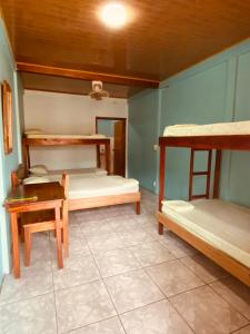 a room with three bunk beds and a table at Cabinas Popular in Puerto Viejo