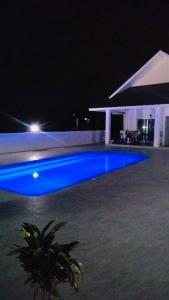 a blue swimming pool at night with a house at Ranch Seda Mosegaard in Amphoe Khukhan