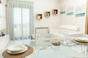 un soggiorno bianco con tavolo e sedie in vetro di La Collina sul Mare Apartments a Petacciato