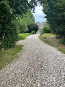 a gravel road with a bench on the side at Cosy cottage in the heart of the Cotswolds in Cirencester