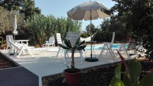 eine Terrasse mit einem Tisch, einem Sonnenschirm und Stühlen in der Unterkunft Quinta Laranjal da Arrabida in Palmela