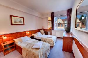 ein Hotelzimmer mit 2 Betten und einem TV in der Unterkunft Hotel Irottkö in Kőszeg