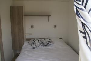 a bed with two pillows on top of it at Les Roulottes & Cottages du Moulin in Chenillé-Changé