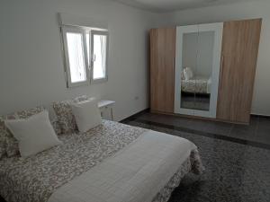 a white bedroom with a bed and a mirror at Casa Luisi in Playa Honda