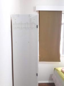 einen weißen Kühlschrank in einem Zimmer mit Fenster in der Unterkunft Lindo quarto na Praia de Botafogo in Rio de Janeiro