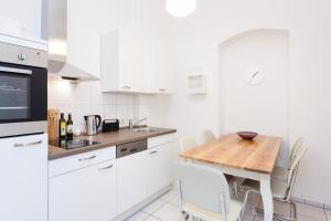 Apartment Berlin Zentrum في برلين: مطبخ مع طاولة خشبية ودواليب بيضاء
