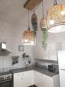 eine Küche mit weißen Schränken und Hängelampen in der Unterkunft Acogedor apartamento con excelente ubicación. in Santa Cruz de Tenerife