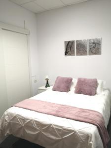 Un dormitorio blanco con una cama grande con almohadas moradas en Acogedor apartamento con excelente ubicación., en Santa Cruz de Tenerife