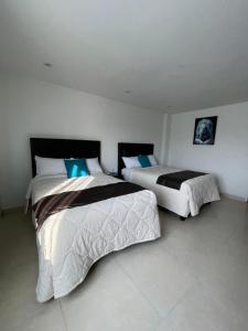 two beds in a room with white walls at ABERDEEN HOTEL DOLORES HIDALGO in Dolores Hidalgo