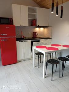 Il comprend une cuisine équipée d'un réfrigérateur rouge et d'une table avec des chaises. dans l'établissement Domek na Jodłowej, à Odargowo