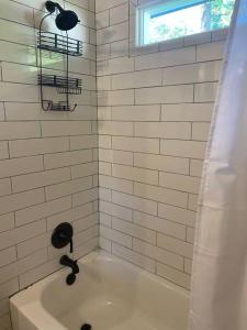 baño de azulejos blancos con bañera y ventana en Cozy 2-bedroom Farmhouse with parking on premise, en Smyrna