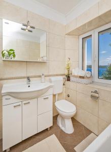 łazienka z umywalką, toaletą i oknem w obiekcie Apartman Daniela w mieście Sobra