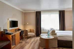 a hotel room with a bed and a tv at Hotel Wilhelm Busch in Norderstedt