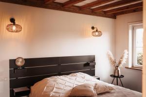 een slaapkamer met een zwart hoofdeinde en 2 verlichting bij -NIEUW- Luxe & sfeervol Vakantiehuis Tholen in Tholen