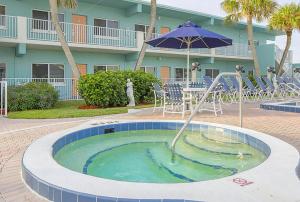 a pool with an umbrella and chairs and a table with an umbrella at Via Roma Beach Resort in Bradenton Beach