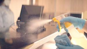 a person in blue gloves spraying a window with a brush at Via Roma Beach Resort in Bradenton Beach