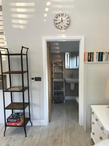 a room with a clock on the wall and a shelf at Cosy cottage in the heart of the Cotswolds in Cirencester