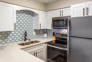 a kitchen with white cabinets and a stainless steel refrigerator at Via Roma Beach Resort in Bradenton Beach