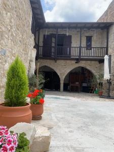 ein Steingebäude mit einem Balkon und Blumen in Töpfen in der Unterkunft Afames House - Beautiful Traditional House in Omodos