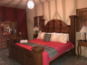 a bedroom with a large wooden bed with red sheets at Hotel Rinconada in San Miguel de Allende