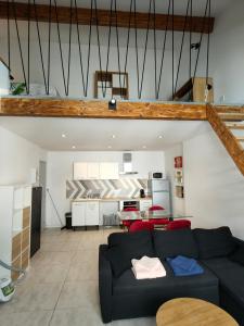 a living room with a black couch and a kitchen at Joli apparemment type Loft in Cavaillon