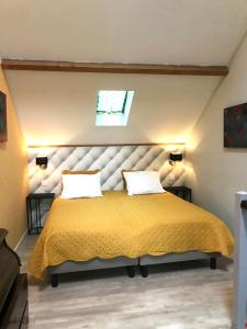a bedroom with a large yellow bed with two pillows at Maisonnette la Grue - Vallée de la Dordogne in Aubazines