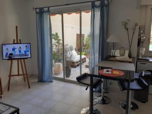 ein Wohnzimmer mit Fernseher und Tisch und Stühlen in der Unterkunft Studio Terrasse Proche Palais des Festivals in Cannes