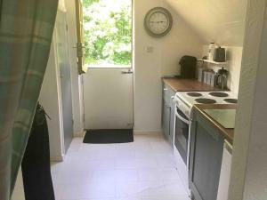 a small kitchen with a clock on the wall at Self Catering Apartment, Jurassic Coast/Dorset in Wareham