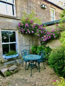 una mesa y sillas frente a un edificio con flores en Key Cottage, sleeps 8 en Brimscombe