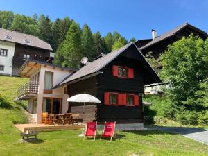 a house with chairs and an umbrella in front of it at Chalet Verdino in Bad Kleinkirchheim