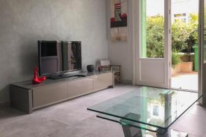 un soggiorno con TV e tavolo in vetro di Charming townhouse with garden in the City of Love a Parigi