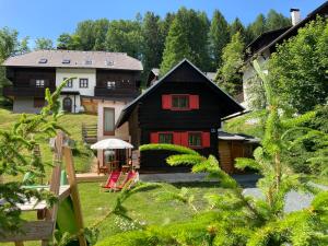 una casa con puertas rojas y sillas rojas en el patio en Chalet Verdino, en Bad Kleinkirchheim