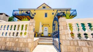 una casa amarilla con puerta y escaleras en Planikovica Apartments, en Trogir