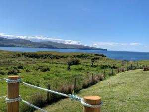 a fence on a hill with a view of the ocean at Coral Cabins in Dunvegan