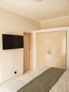 Schlafzimmer mit einem Bett und einem Flachbild-TV an der Wand in der Unterkunft Kasuda - self contained room in Livingstone in Livingstone