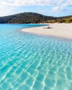 una playa de agua azul y una playa de arena en IL TRAMONTO, en SantʼAnna Arresi