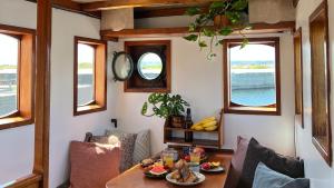 a dining room with a table and two windows at Varra Water - Unique Boat Accomodation - Bornholm in Neksø